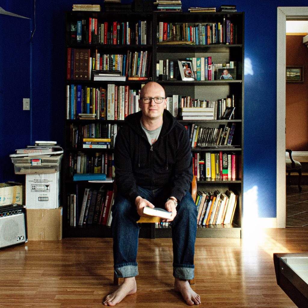 Scott Ritchings sitting in front of books.